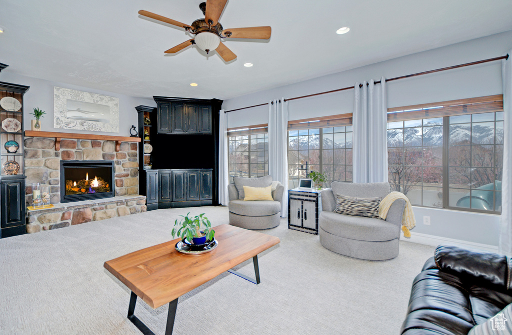 Carpeted living room featuring ceiling fan and a fireplace