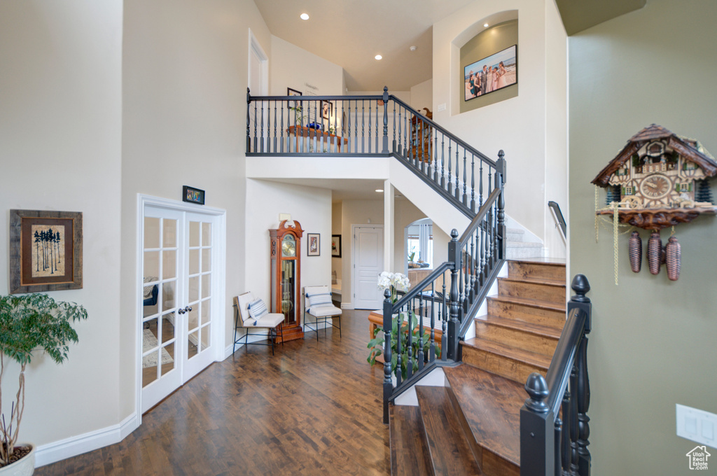 Stairway featuring french doors, dark hardwood / wood-style flooring, and a high ceiling