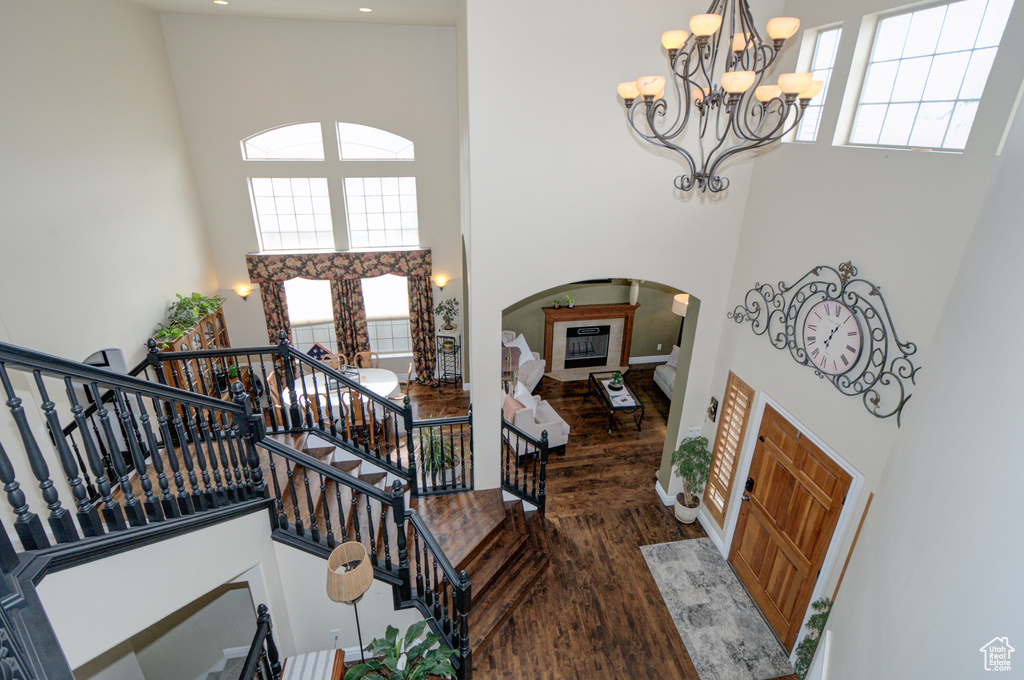 Foyer entrance featuring dark hardwood / wood-style floors, a towering ceiling, and a chandelier