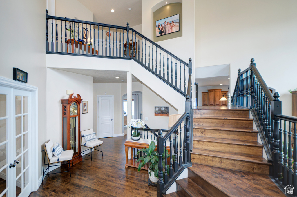 Stairway with a high ceiling, french doors, and dark wood-type flooring