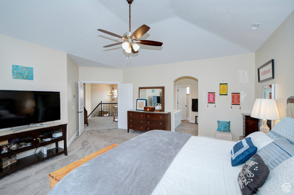 Bedroom featuring ceiling fan with notable chandelier, ensuite bath, light carpet, and vaulted ceiling