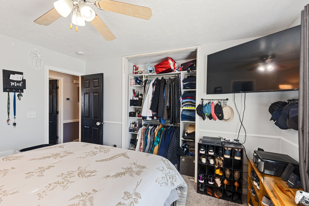 Carpeted bedroom featuring a closet, a textured ceiling, and ceiling fan