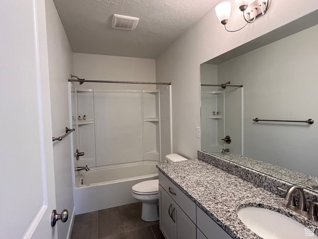 Full bathroom with vanity with extensive cabinet space, shower / bath combination, toilet, and a textured ceiling