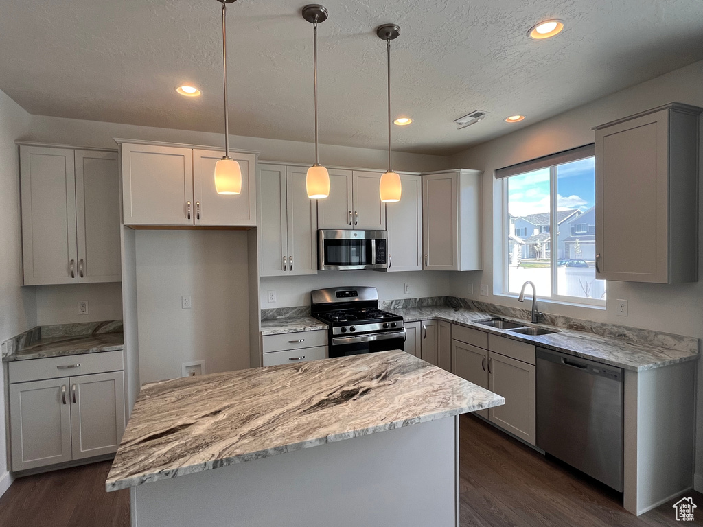 Kitchen featuring decorative light fixtures, white cabinets, stainless steel appliances, and dark wood-type flooring