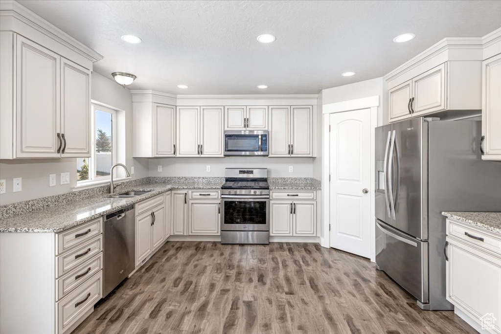 Kitchen featuring wood-type flooring, stainless steel appliances, white cabinets, and sink
