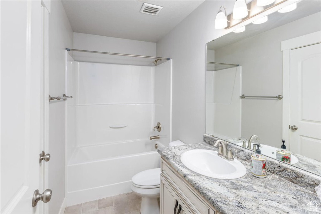 Full bathroom featuring washtub / shower combination, oversized vanity, toilet, and tile flooring
