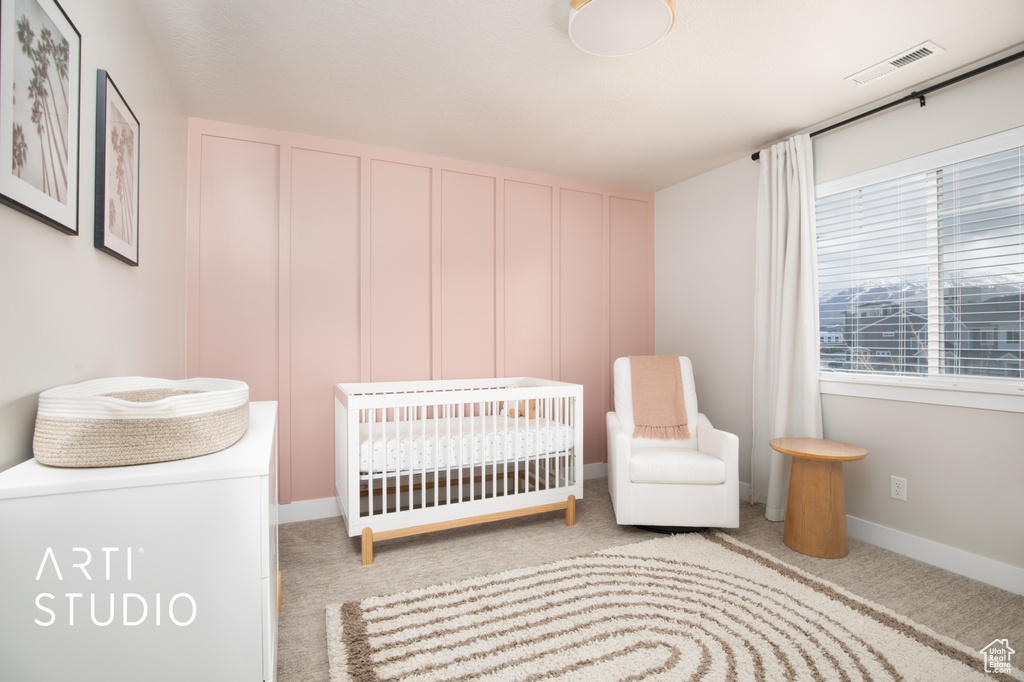 Unfurnished bedroom featuring a crib and light carpet