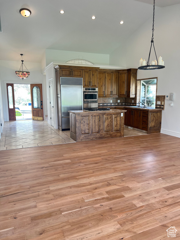 Kitchen featuring light hardwood / wood-style flooring, tasteful backsplash, stainless steel appliances, and a center island