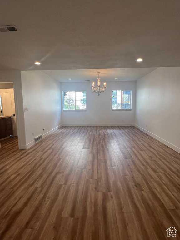 Unfurnished room featuring dark hardwood / wood-style floors and an inviting chandelier