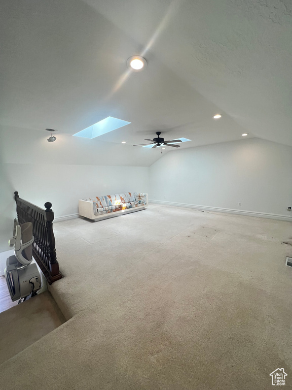 Interior space featuring light colored carpet, ceiling fan, and lofted ceiling with skylight