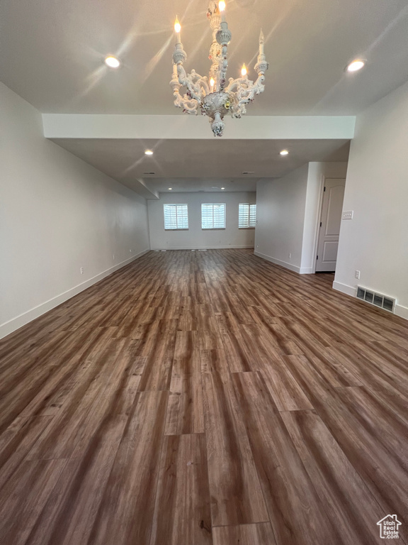 Unfurnished room with dark hardwood / wood-style flooring and a notable chandelier