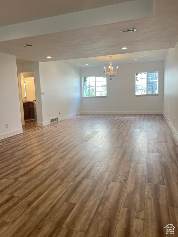 Empty room featuring dark hardwood / wood-style floors, plenty of natural light, and a chandelier
