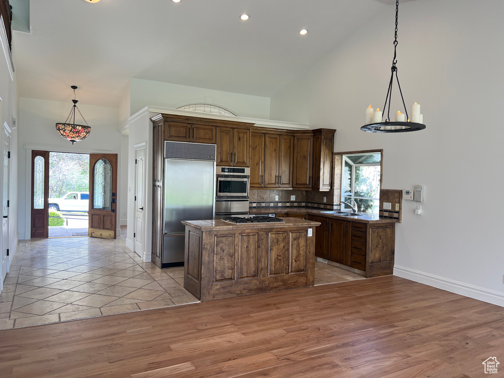 Kitchen featuring backsplash, a kitchen island, appliances with stainless steel finishes, and light wood-type flooring