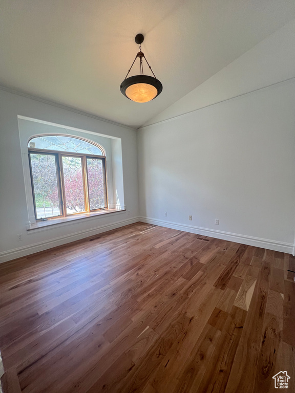 Spare room featuring lofted ceiling and dark hardwood / wood-style floors