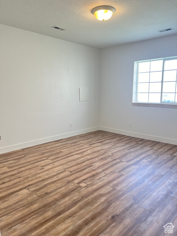 Unfurnished room featuring a textured ceiling and dark wood-type flooring