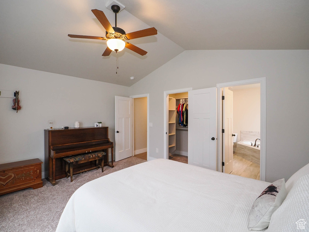 Bedroom featuring light colored carpet, a spacious closet, vaulted ceiling, ceiling fan, and a closet