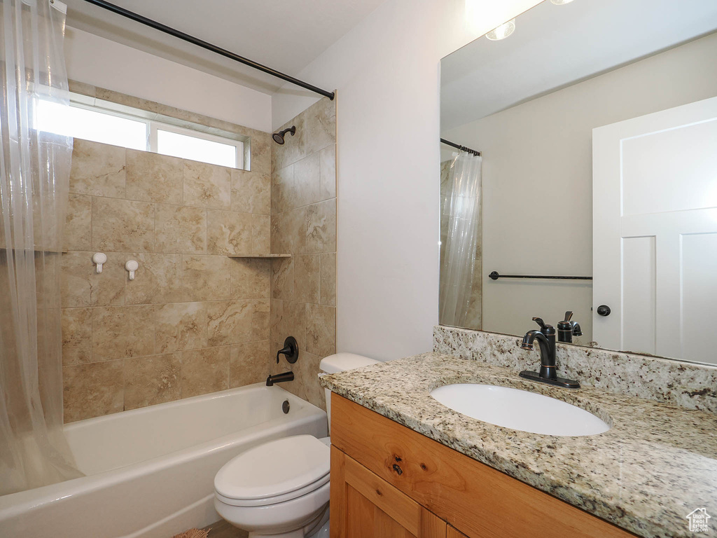 Full bathroom with oversized vanity, shower / bathtub combination with curtain, and toilet