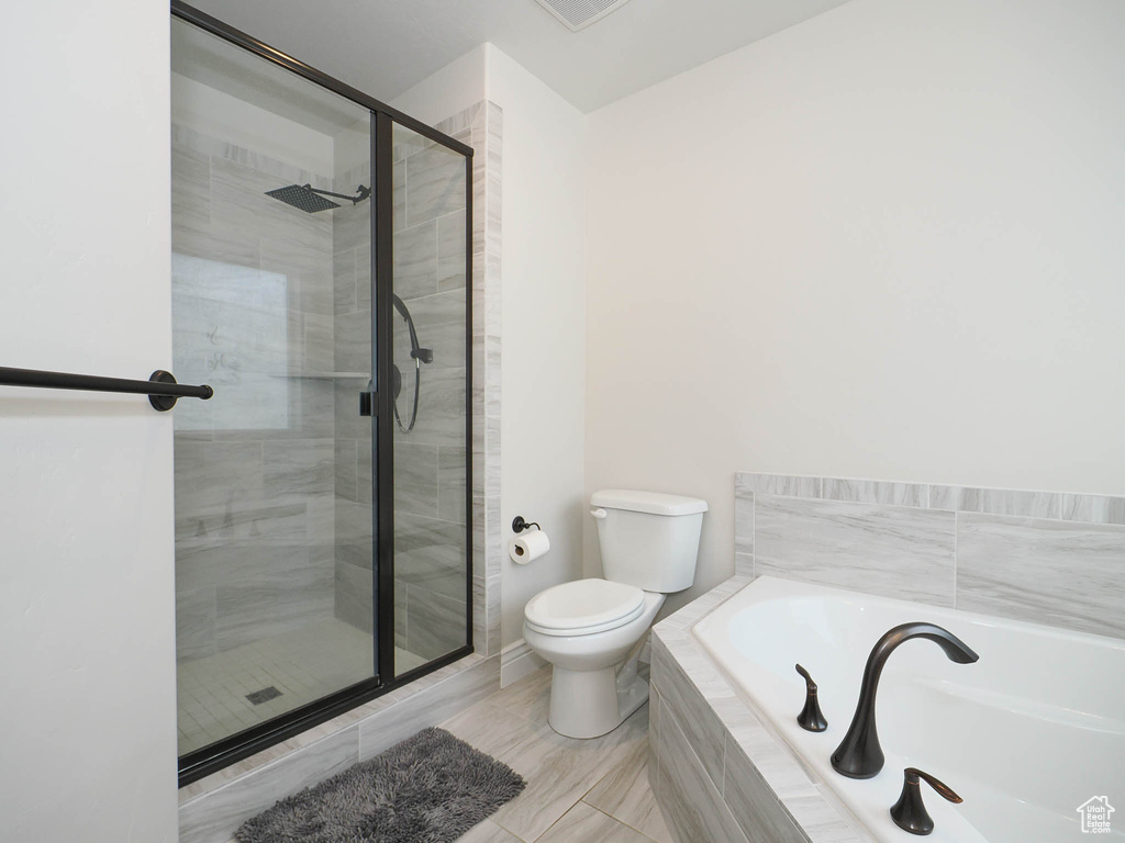 Bathroom featuring tile flooring, separate shower and tub, and toilet