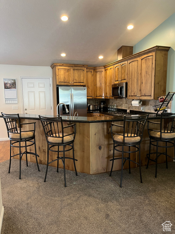 Kitchen featuring a kitchen breakfast bar, stainless steel appliances, and carpet