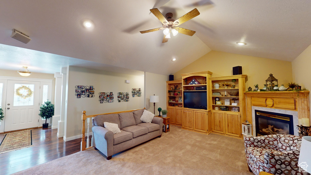Living room featuring light carpet, vaulted ceiling, ceiling fan, and a high end fireplace