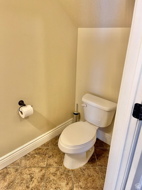Bathroom featuring tile flooring, toilet, and a textured ceiling