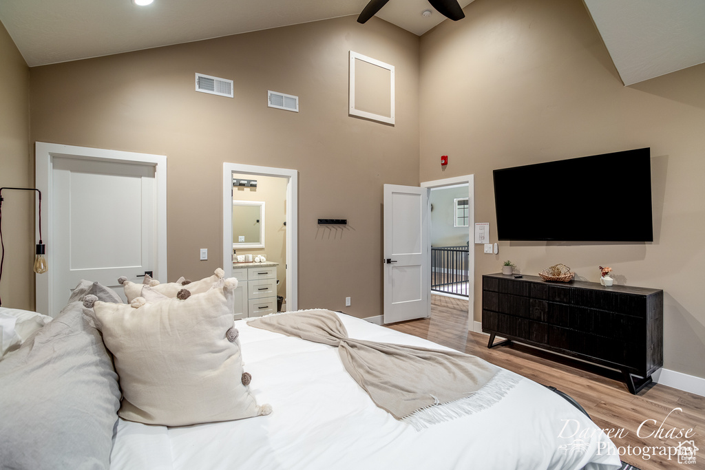 Bedroom with ceiling fan, high vaulted ceiling, light wood-type flooring, ensuite bath, and beam ceiling