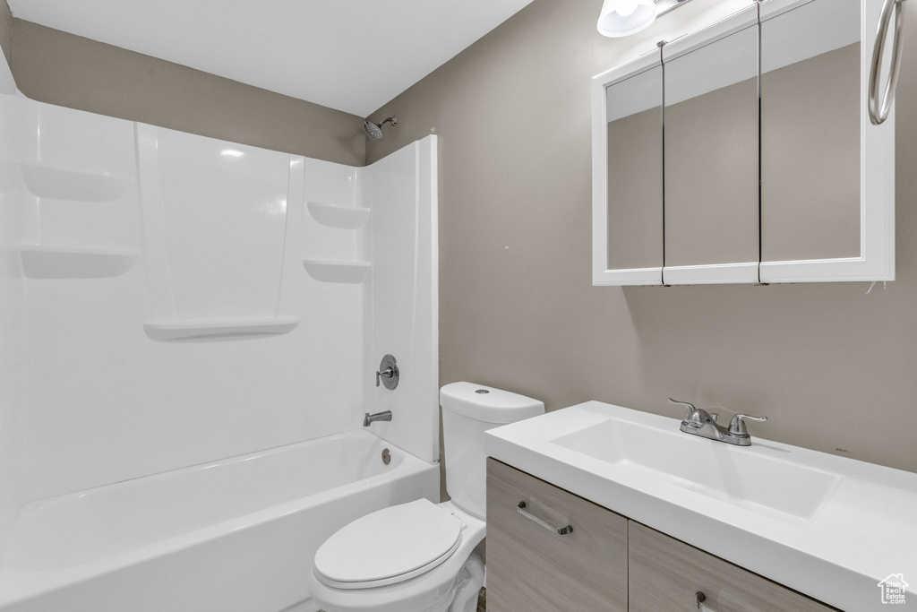 Full bathroom featuring shower / washtub combination, toilet, and vanity with extensive cabinet space