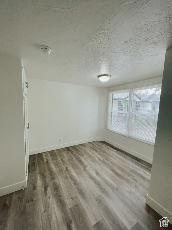 Empty room featuring a textured ceiling and hardwood / wood-style flooring