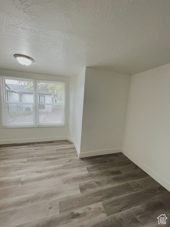 Unfurnished room featuring hardwood / wood-style floors and a textured ceiling