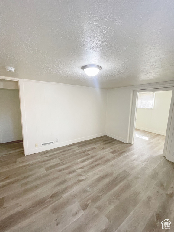 Unfurnished room with light hardwood / wood-style flooring and a textured ceiling