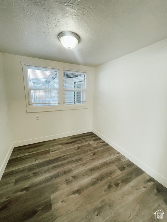 Unfurnished room featuring a healthy amount of sunlight, dark hardwood / wood-style floors, and a textured ceiling