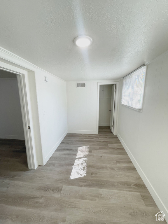 Unfurnished room with light hardwood / wood-style flooring and a textured ceiling