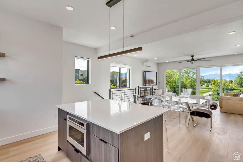 Kitchen featuring a kitchen island, plenty of natural light, stainless steel microwave, and light wood-type flooring