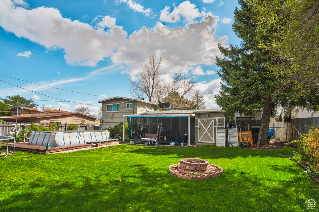 View of yard featuring a fire pit and a fenced in pool