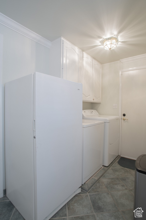 Laundry area with cabinets, ornamental molding, dark tile flooring, and washing machine and dryer