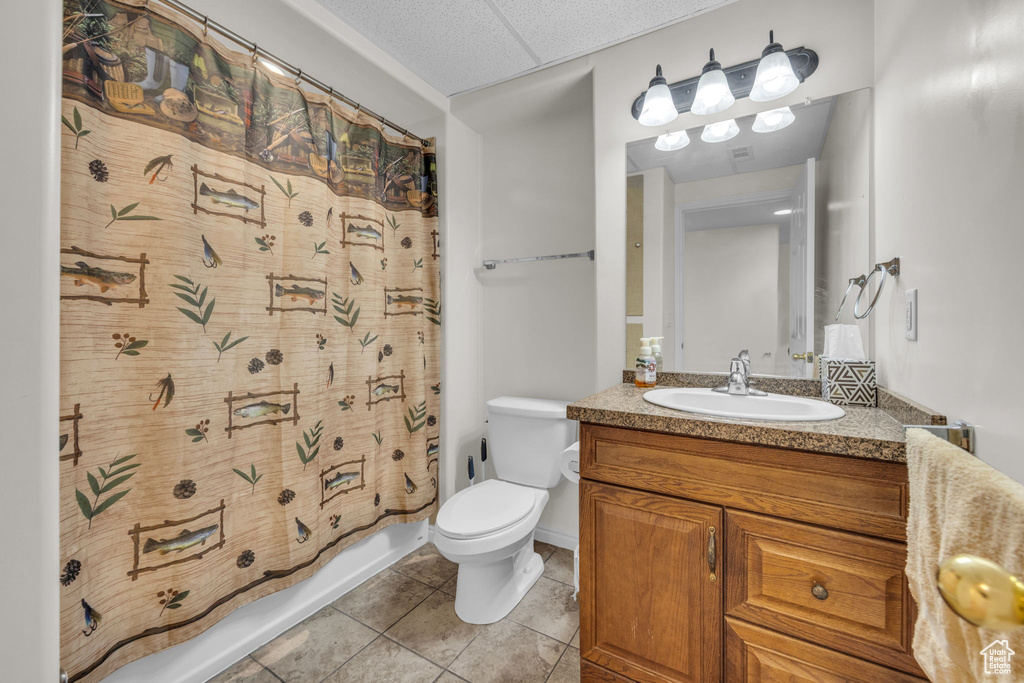 Full bathroom with tile flooring, shower / tub combo, vanity with extensive cabinet space, and toilet