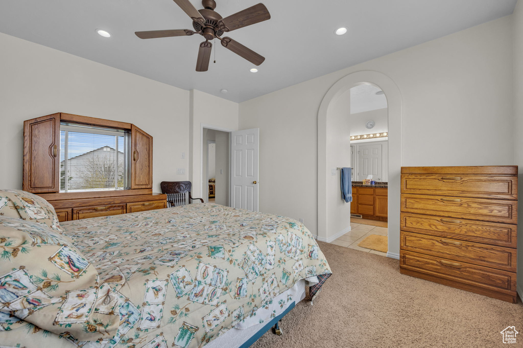 Bedroom with ensuite bath, ceiling fan, and light tile floors