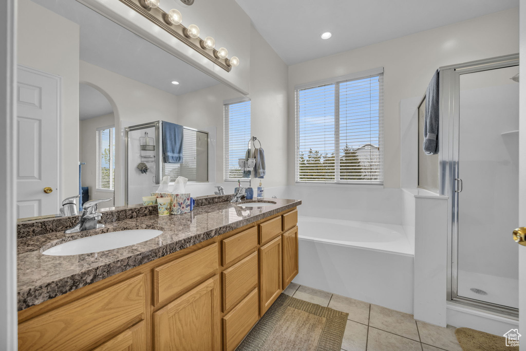 Bathroom with dual sinks, tile floors, independent shower and bath, and large vanity