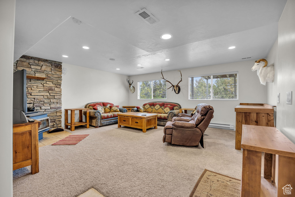 Living room with light carpet, a baseboard heating unit, and a wood stove