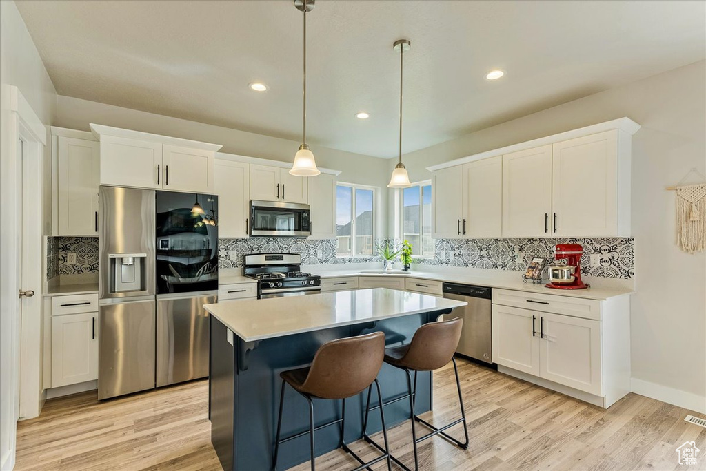 Kitchen featuring backsplash, a kitchen island, stainless steel appliances, and white cabinets