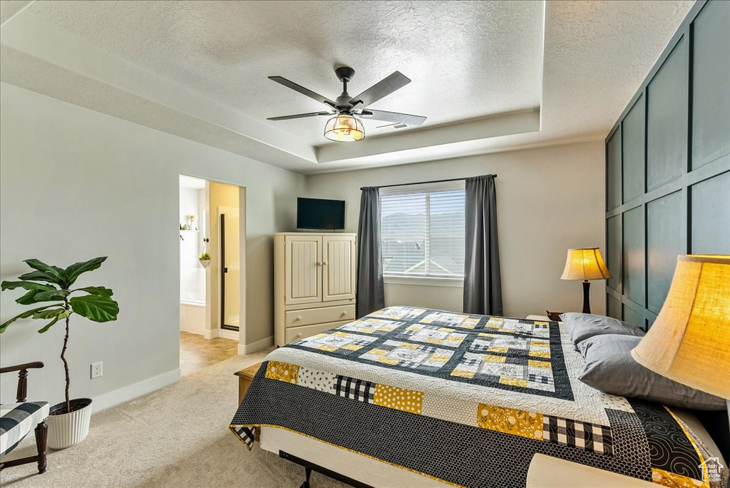 Carpeted bedroom with ceiling fan, a tray ceiling, and a textured ceiling