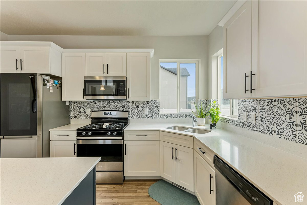 Kitchen with sink, appliances with stainless steel finishes, and white cabinetry