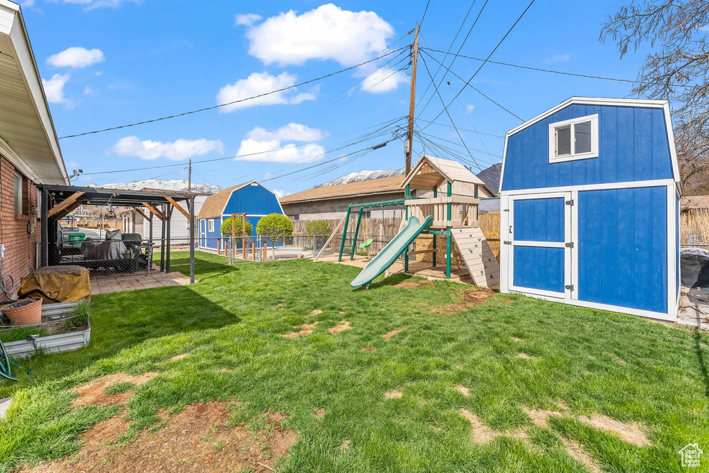 View of yard featuring a storage unit and a playground