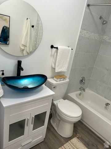 Full bathroom with tiled shower / bath combo, wood-type flooring, vanity, and toilet