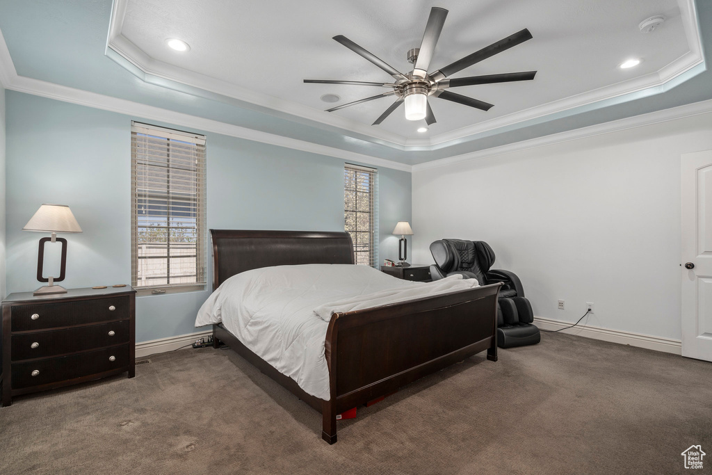 Bedroom featuring dark colored carpet, ceiling fan, a tray ceiling, and crown molding