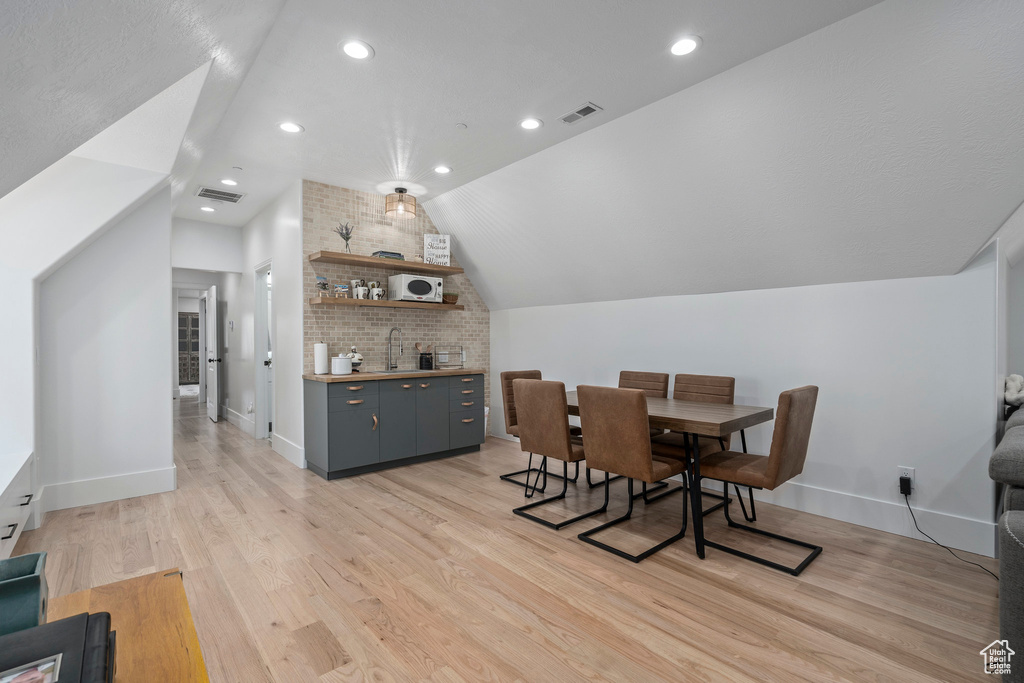 Dining space featuring vaulted ceiling, light hardwood / wood-style floors, and sink