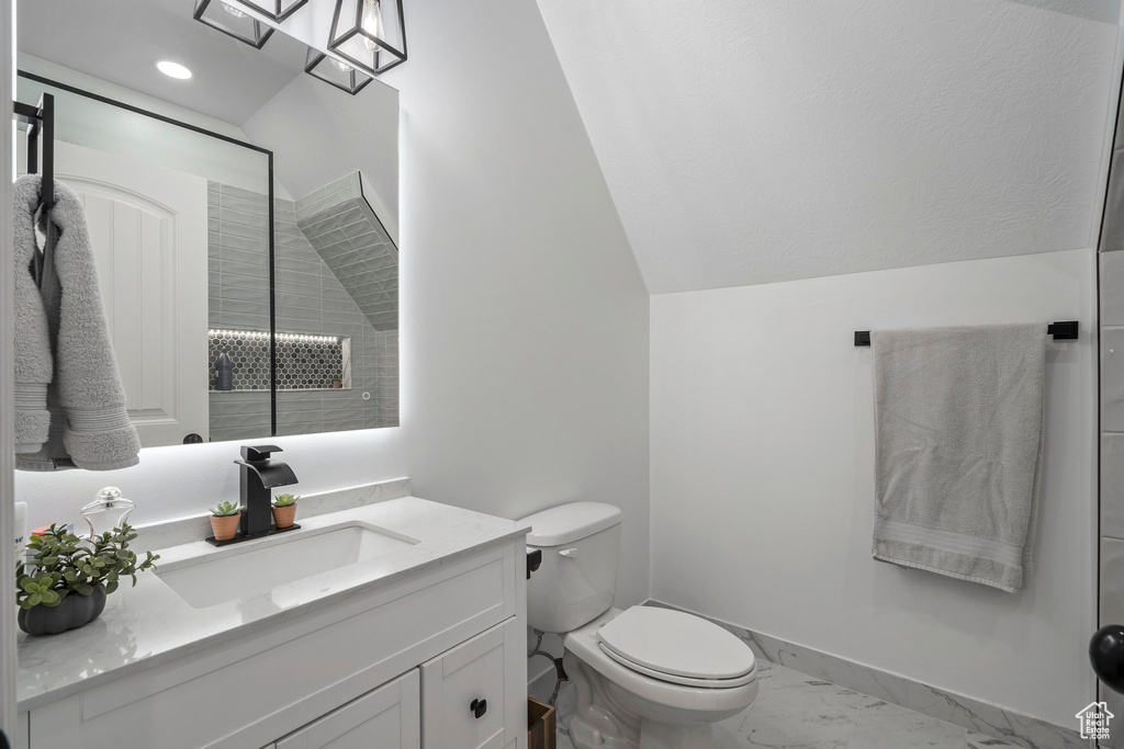 Bathroom with oversized vanity, vaulted ceiling, toilet, and tile flooring