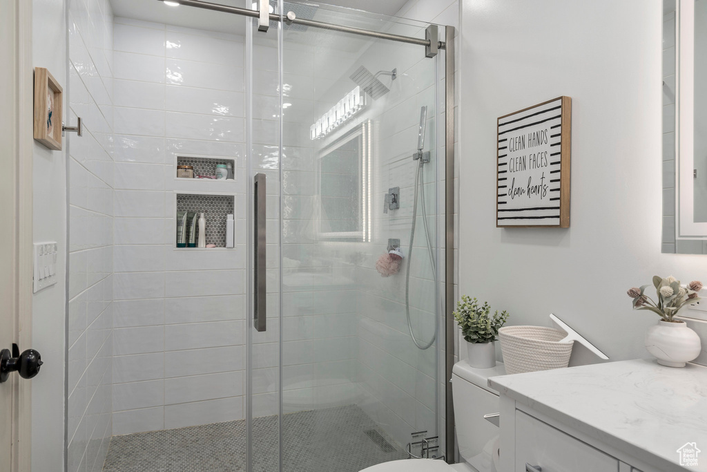 Bathroom with a shower with shower door, vanity, and toilet
