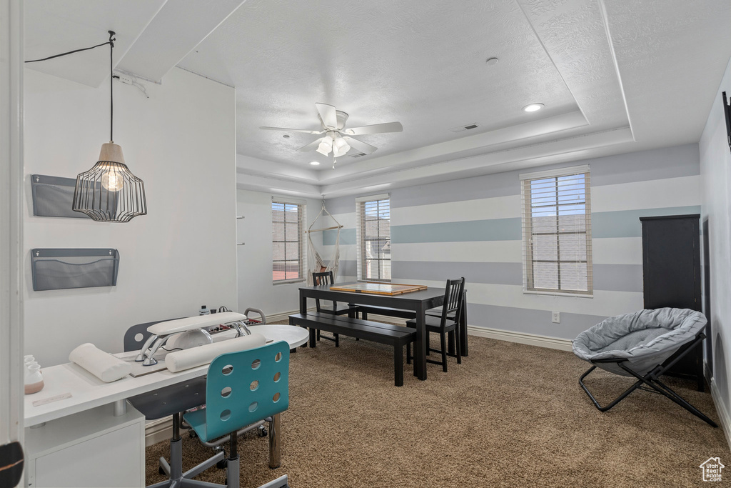 Carpeted office featuring ceiling fan and a tray ceiling