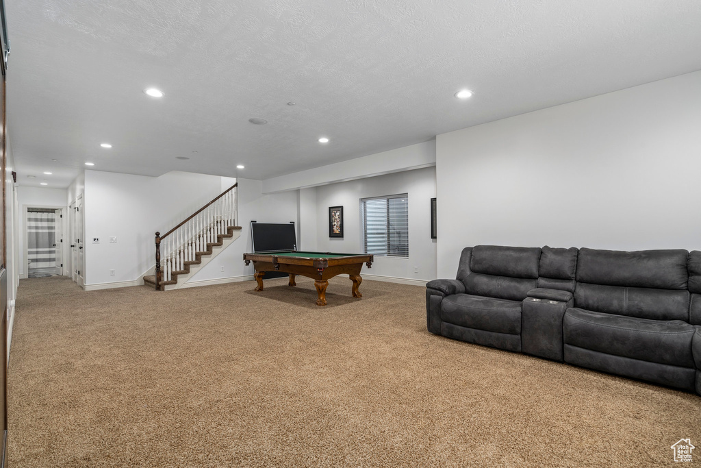 Carpeted living room with a textured ceiling and pool table